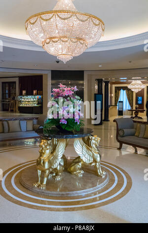 Una grande lobby, una spaziosa hall con un enorme lampadario di cristallo, arredamento, una tabella di fiori con golden grifoni . Per il vostro design Foto Stock