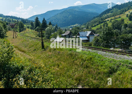 Il binario ferroviario circonda il villaggio nella valle tra il verde delle montagne dei Carpazi . Per il vostro design Foto Stock