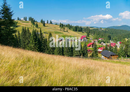 Il bianco delle nuvole galleggianti in distanza sopra le cime della montagna e un accogliente villaggio di nascondersi dietro il verde di alberi di alto fusto . Per il vostro design Foto Stock