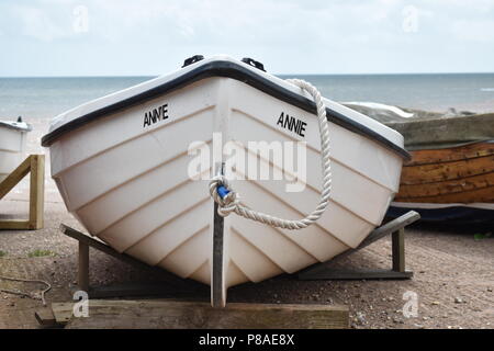 La prua di una piccola barca bianca di nome Annie in appoggio sui supporti vicino al mare con il mare sullo sfondo a Sidmouth, nel Devon , Inghilterra Foto Stock