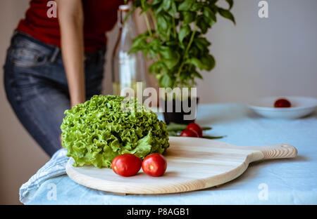 Giovane donna che indossa jeans cucina vegetariana sana detox cibo. Ingredienti e preparazione per una sana cucina italiana Foto Stock