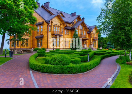 Un sgangherate sentiero acciottolato in un parco ben tenuto di fronte a un enorme palazzo di legno tra alti alberi verdi e arbusti ornamentali . Per il vostro design Foto Stock