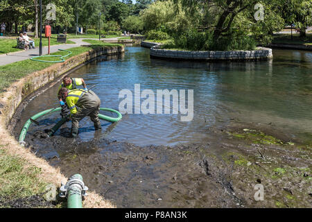Lavoratori che utilizzano una pompa di aspirazione per rimuovere il fango e limo in un lago. Foto Stock