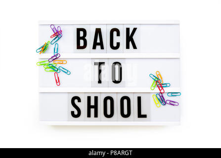 Si torna a scuola scritto su una moderna scatola di luce su uno sfondo bianco e colorati di fermagli per carta Foto Stock