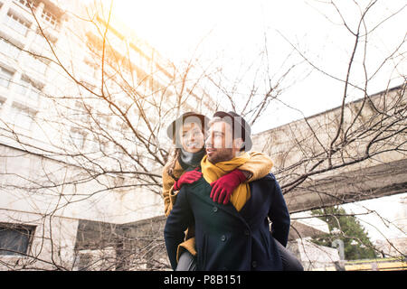 Uomo bello dando piggyback ride felice ragazza Foto Stock