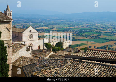 Piastrella tetti di Assisi, Italia con la Basilica di Santa Chiara in background Foto Stock