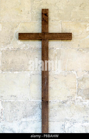 Vecchia croce di legno sul muro di pietra Foto Stock