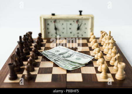 Scacchiera con contanti e figure vicino a scacchi orologio isolato su bianco Foto Stock