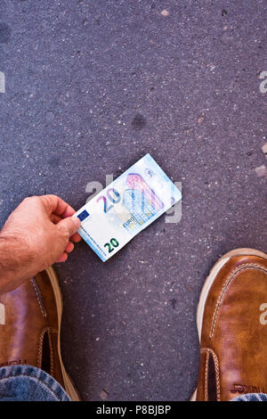 Ricerca di una banconota sulla strada Foto Stock