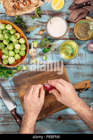 Man mano la cottura di cibi sani con cavolini di Bruxelles sul tavolo di legno, vista dall'alto. Cibo sano concetto Foto Stock