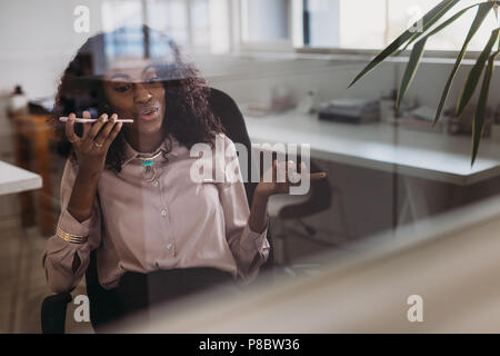 Imprenditrice in abbigliamento formale a parlare su telefono cellulare su altoparlante seduti a casa. Donna imprenditore managing business da casa discutendo wor Foto Stock