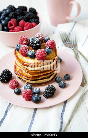 Frittelle con diverse bacche di rosa della piastra sulla tabella, vista laterale. Foto Stock