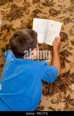 Ragazzo lettura libro sul tappeto. Il sig. © Myrleen Pearson Foto Stock