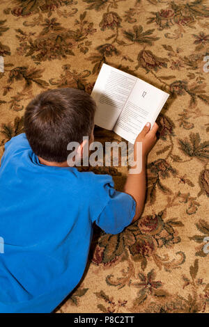 Ragazzo lettura libro sul tappeto. Il sig. © Myrleen Pearson Foto Stock