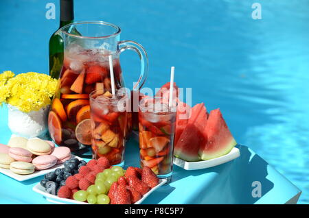 Party in piscina con sangria brocca, cocktail di frutta e rinfreschi a bordo piscina. Stile di vita estiva, topica vacanza, divertimento e relax tema. Foto Stock