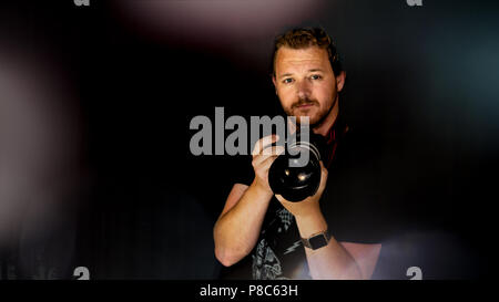 Un fotografo professionista mantiene la sua fotocamera vicino al suo volto. Foto Stock