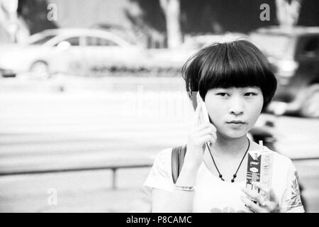 Un giovane studente sul suo telefono cellulare nelle strade di Guilin Cina, tipico dei giovani di oggi e lo stile di vita moderno. Foto Stock