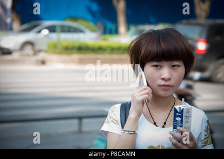 Un giovane studente sul suo telefono cellulare nelle strade di Guilin Cina, tipico dei giovani di oggi e lo stile di vita moderno. Foto Stock