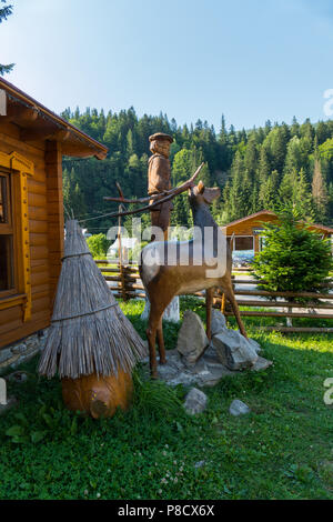 Modello di una foresta cervi sullo sfondo di una capanna di legno verde e alberi di conifere . Per il vostro design Foto Stock