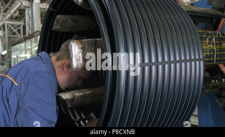 RUSSIA, ANGARSK - Giugno 8, 2018: bobina bobina di filettatura tubo. Fabbricazione di plastica tubazioni acqua fabbrica. Processo per la fabbricazione di tubi di plastica sulla macchina utensile con l uso dell acqua e la pressione dell'aria. Foto Stock