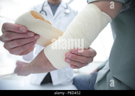 Ortopedico applicando un bendaggio sulla mano del paziente in clinica Foto Stock