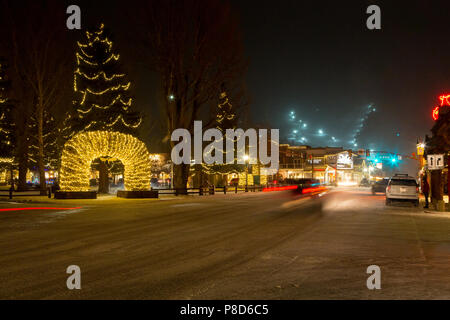 Downtown Jackson illuminato con luci di Natale su una sera d'inverno con la neve Re Ski Resort notte di funzionamento di equitazione in background. Jackson, Wyo Foto Stock