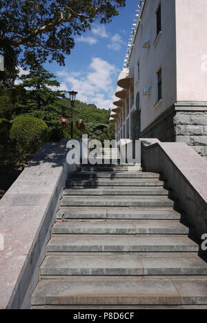 Una scaletta con gradini di granito salendo lungo la costruzione e pendii delle montagne in lontananza . Per il vostro design Foto Stock