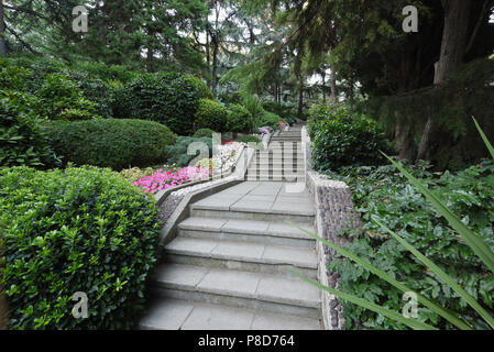 Vicolo in un bellissimo parco piantati con una decorazione cespugli e fiori colorati vicino al cordolo . Per il vostro design Foto Stock