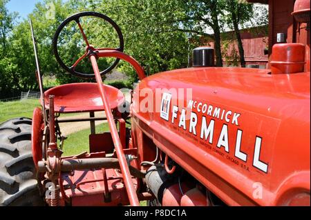 Ben mantenuta, rosso McCormick Farmall trattore parcheggiato su cascina in paesaggio rurale del Wisconsin, USA Foto Stock