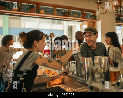 Sorridente patrono ordinare un drink in un bar alla moda Foto Stock