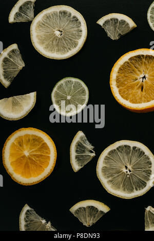 Citrus su uno sfondo nero. Molte fette di limone, arancio, calce si trovano insieme. Un sacco di frutta. Vitamine e un snack sani. Foto Stock