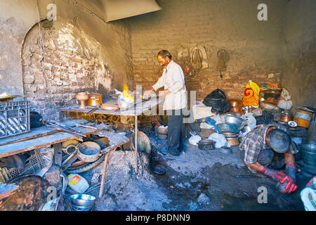 KERMAN, IRAN - 15 ottobre 2017: Il workshop di pentole pulitori, che utilizzano il fuoco, sabbia e piccole pietre per pulire, ri-stagione e ripristinare le vecchie pentole, Foto Stock