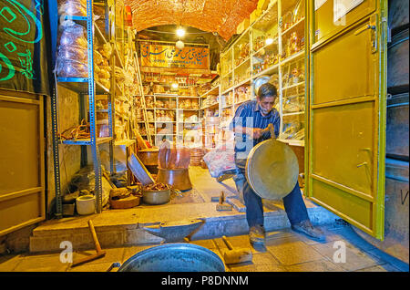 KERMAN, IRAN - 15 ottobre 2017: il ramaio funziona con un martello, rendendo la panoramica in entrata al suo negozio-laboratorio, situato in Ganjali Khan Baza Foto Stock