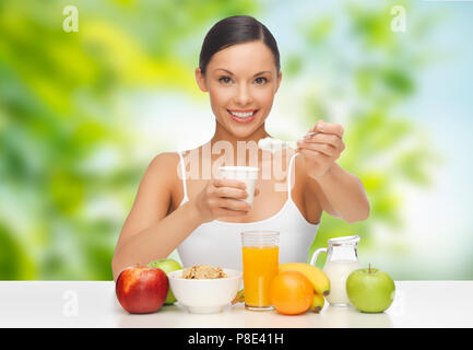 Donna con frutta mangiare yogurt per la prima colazione Foto Stock