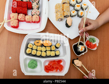 La cucina giapponese. Gli amici di mangiare panini e sushi con bacchette. Sul tavolo un paio di piastre con set, salsa e wasabi. Foto Stock