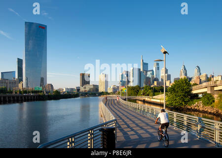 Lo Skyline di Philadelphia e Schuylkill River Park Boardwalk con ciclista al tramonto, Philadelphia, Pennsylvania, STATI UNITI D'AMERICA Foto Stock