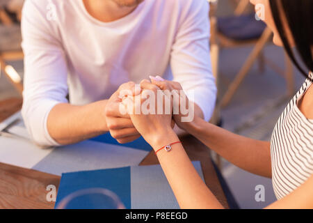 Bella donna che indossa un bracciale di Nizza toccando le mani del suo uomo Foto Stock