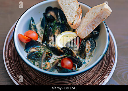 Cozze piatto con un po' di pane e pomodorini Foto Stock