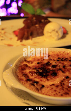 Cucina francese: crème brûlée (messa a fuoco) e Tarte Tatin con gelato alla vaniglia (al di fuori della messa a fuoco) - Annecy, Haute Savoie, Francia Foto Stock