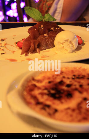 Cucina francese: Tarte Tatin con gelato alla vaniglia (messa a fuoco) e crème brûlée (al di fuori della messa a fuoco) - Annecy, Haute Savoie, Francia Foto Stock