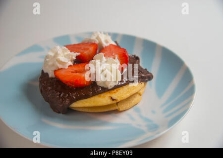 Pancake con cioccolato, fragole e panna. Foto Stock