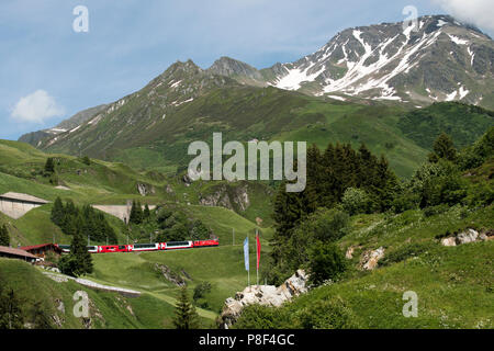 Andermatt nel Cantone di Uri, Svizzera, mostrando Swiss Mountain Trains-Matterhorn Gotthard Bahn- salendo verso Oberalp Pass e Swiss flag. Foto Stock