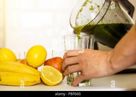 Donna miscelazione di spinaci, banane, limone e mele per fare un sano frullato verde. Uno stile di vita sano concetto Foto Stock