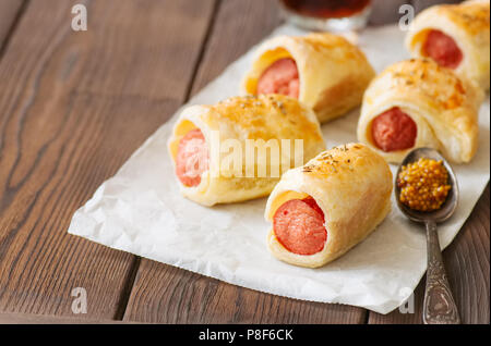 Suini in un planket. Pasta sfoglia panini con salsicce su un sfondo di legno. Il fast food o birra snack concetto. Foto Stock