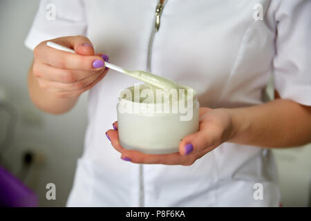 Cosmetologo mani, preparare la maschera di pulizia. Close-up shot di vaso con bellezza viso Crema Foto Stock