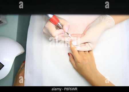 Master per unghie rimuovere smalto per unghie nel salone di bellezza con una speciale macchina elettrica - hardware manicure. La bellezza e la cura delle unghie concept Foto Stock