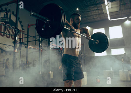 Montare il giovane uomo il sollevamento barbells lavorando in una palestra Foto Stock