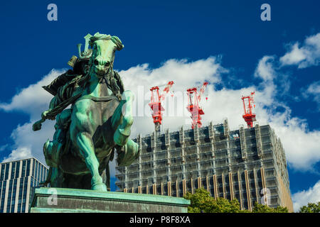 Costruzione di Giappone tra tradizione e modernità. Un moderno grattacielo è in costruzione dietro un vecchio guerriero samurai statua nel centro della citta'. Foto Stock