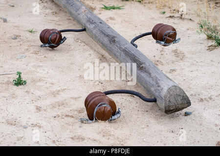 Un vecchio legno polo di alimentazione giacente a terra. Rotture di rete elettrica. Stagione di estate. Foto Stock