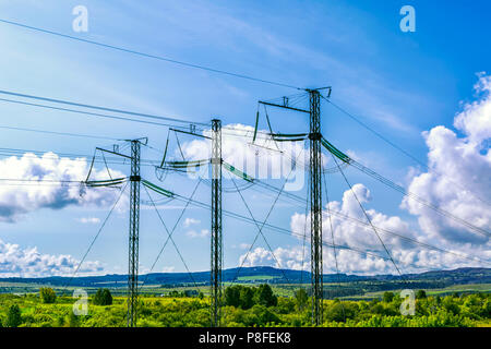 Alta tensione torri di trasmissione oltre il cielo blu. Energia elettrica sul filo il paesaggio rurale dello sfondo. Foto Stock